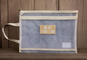 Blue document bag with beige trim and a label reading '语文' on the front, resting on a wooden surface.