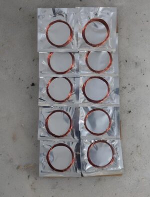 Multiple aluminum foil packets arranged in a grid, each containing a circular copper ring.