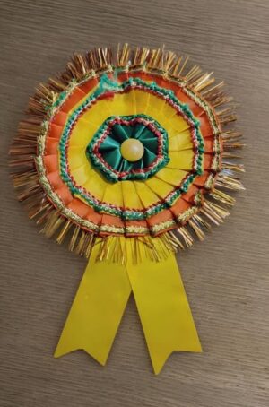 Colorful circular award ribbon with yellow, orange, and green layers, gold fringe, and two yellow streamer tails.