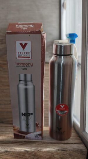Boxed silver stainless-steel vacuum flask and a tall matching water bottle with a blue flip-top cap on a wooden windowsill.