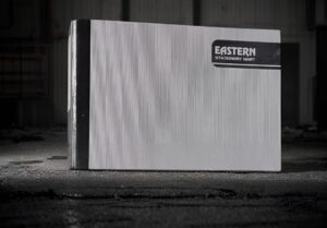 Corrugated cardboard box with an Eastern Stationery Mart label in a dark warehouse setting (black and white).