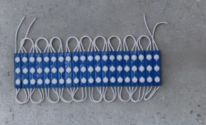 Row of blue modular cable connectors with gray loops laid in a neat row on a concrete surface