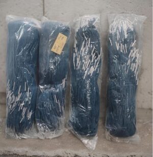 Four blue mop heads wrapped in clear plastic, standing upright against a concrete wall.