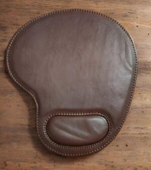 Brown leather gun holster with stitched edges and a small padded pocket near the bottom, shown on a wooden surface.