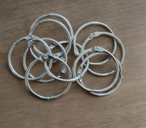 Pile of silver metal bangle bracelets with small clasps on a wooden surface