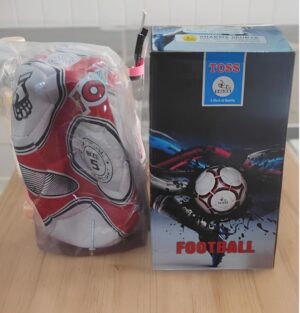 A red-and-white football tucked in plastic beside a blue and black 'TOSS' football box on a wooden surface.