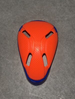 Orange protective knee pad with blue trim and ventilation cutouts lying on a gray floor.