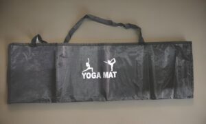 Black yoga mat carry bag with white 'YOGA MAT' logo and two handles laid flat on a neutral background.