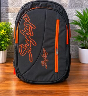 Black backpack with bright orange zippers and orange script branding on the front, placed on a wooden table indoors.