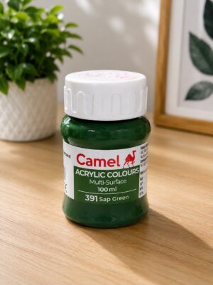 Green Camel acrylic paint bottle (Sap Green, 391), 100 ml, on a wooden table with a plant in the background.