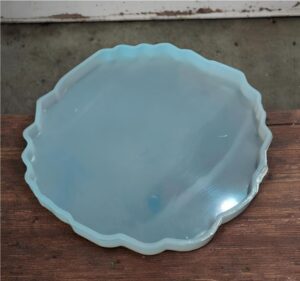 Round light-blue glass plate with a wavy scalloped edge resting on a wooden surface.