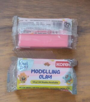 Packaging of Koree Modeling Clay in a pastel-colored wrapper showing 'Modelling Clay' and '50 g | 24 Shades Available' with cartoon animals on the front.