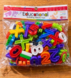 Colorful plastic numbers and math blocks inside a clear bag on a wooden table (educational toy).