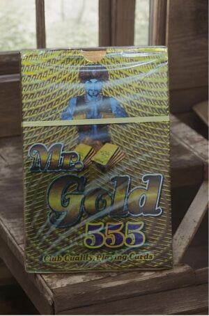 Box of Mr. Gold 555 Club Quality Playing Cards on a wooden surface, with a gold, yellow patterned design and a blue-tinted figure on the front cover.