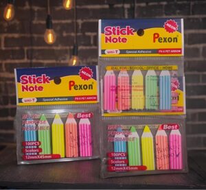Two packs of neon sticky notes in plastic packaging labeled Stick Note Pexon on a dark wood table.