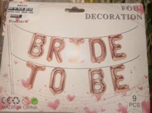 Foil balloon banner spelling 'BRIDE TO BE' on strings, in a bridal decoration package