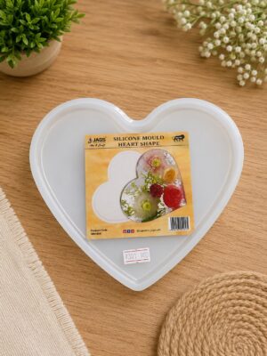 Heart-shaped silicone mould in a white heart tray on a wooden table, packaging on top.