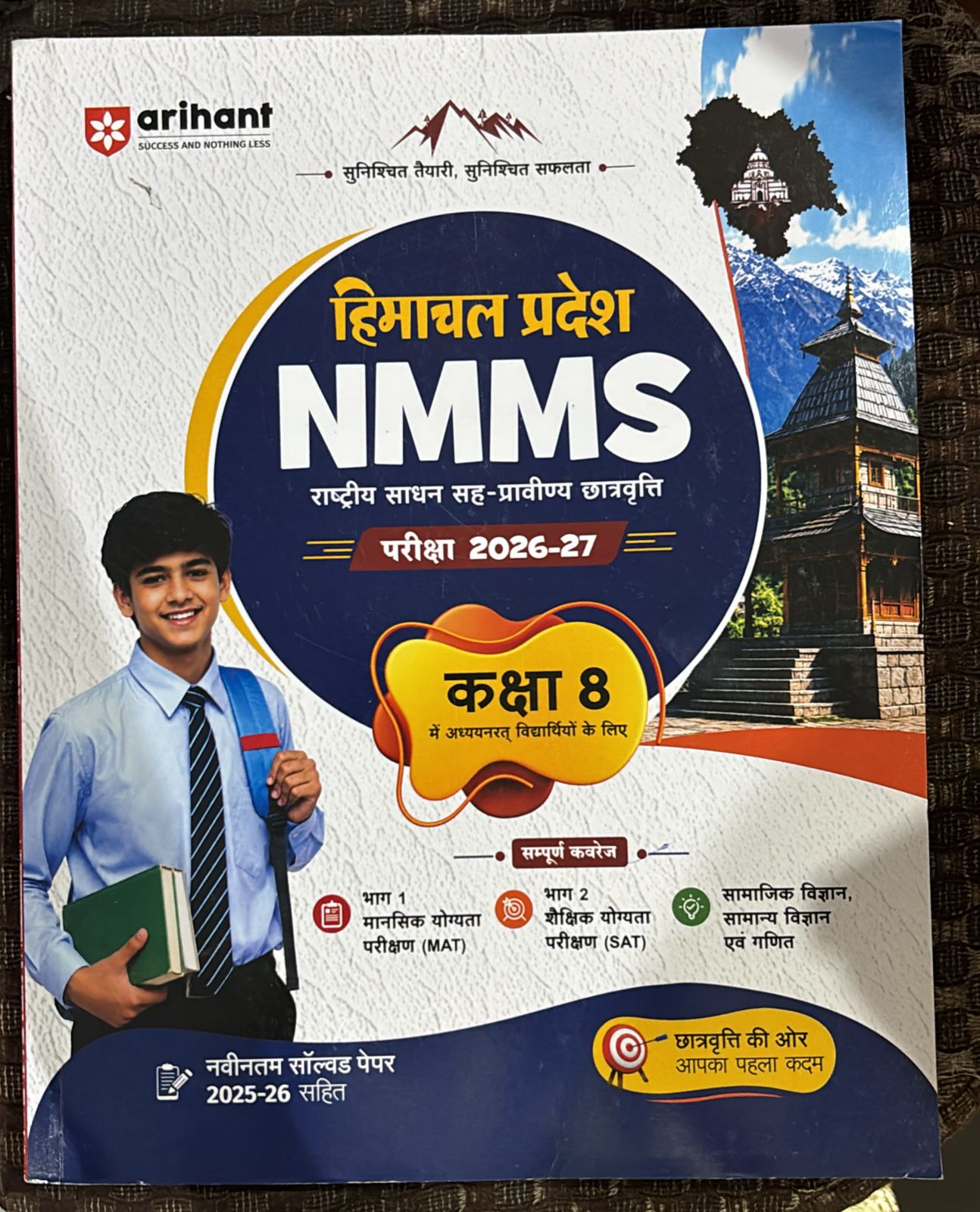 NMMS exam guide cover for Class 8 (2026-27) with student, logos, and Nepali/Indian motifs; decorative circle and mountains on white background.