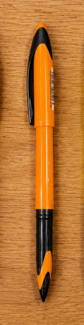 Orange and black marker-style pen lying on a wooden surface, seen from the side with a clip visible on the cap.