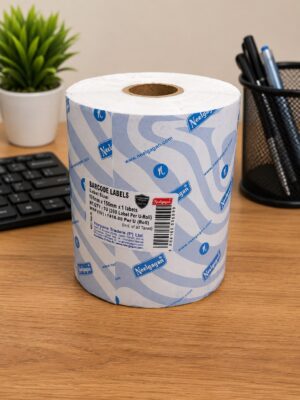 Roll of barcode-label paper on a wooden desk with a plant and pen holder in the background (office supplies).