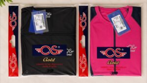 Two packaged jackets in clear plastic: a black jacket on the left and a pink jacket on the right, each with a blue OS logo patch and 'Gold' branding visible.