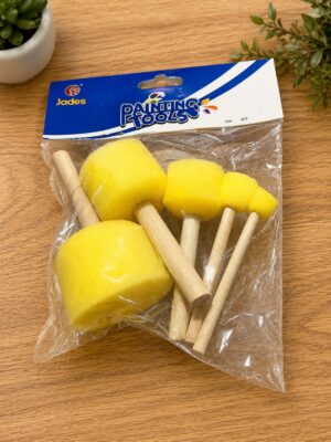 Package of yellow foam brushes with wooden handles inside a plastic bag labeled 'Painting Tools' on a wooden table.