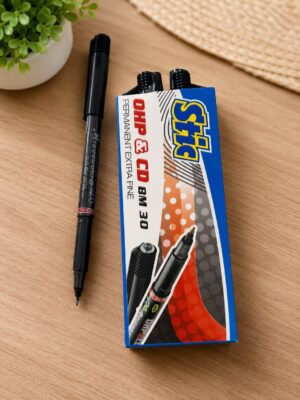 Black felt-tip pen lying on a light wood desk next to a blue Sharpie marker box with two markers visible and a small potted plant in the corner of the image.
