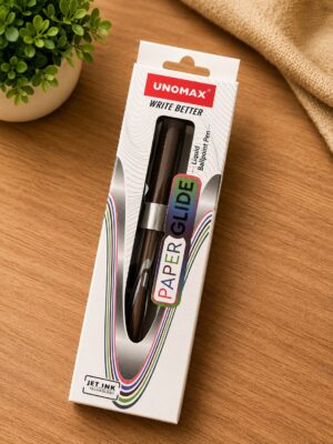Unomax Paper Glide pen in white packaging on a wooden desk beside a small plant, labeled 'WRITE BETTER'