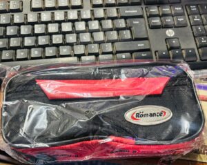 Black and red zippered pouch in plastic wrap on a keyboard, with a metal 'Romance' logo visible.