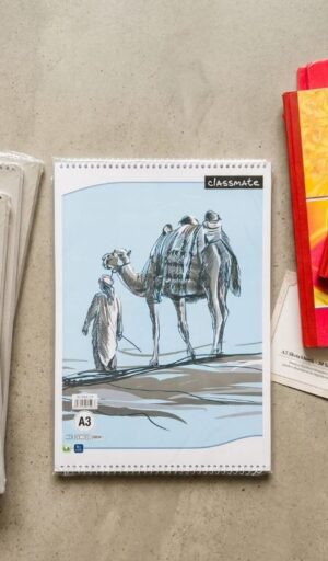 Spiral notebook on a table with a light blue desert illustration showing a person and a camel, labeled 'classmate' at the top right.