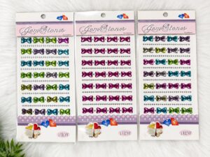 Three packs of colorful bow-shaped gem stickers arranged in rows on a white backing card labeled Gem Stones (packaged craft gems).