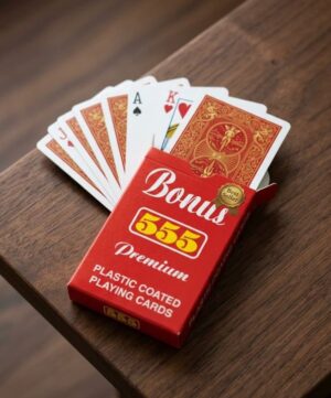 Fanned deck of playing cards on a wooden table with a red Bonus 555 Premium plastic-coated box beside them.