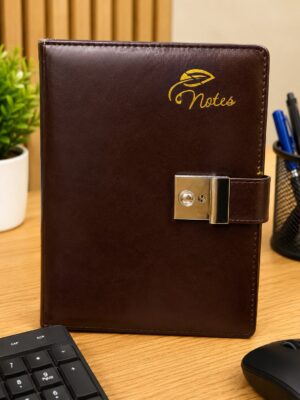 Brown leather notebook with a gold 'Notes' logo and metal clasp on a wooden desk, with a keyboard and mouse nearby.