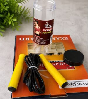 Jump rope with yellow handles and black cord resting on an orange exercise box; a bottle labeled 'Toss Fighter' stands upright nearby.
