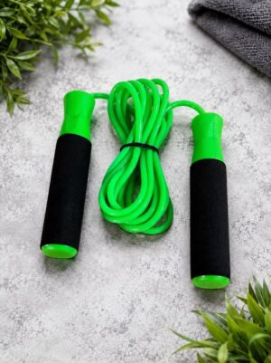Green jump rope with black foam handles on a gray textured surface