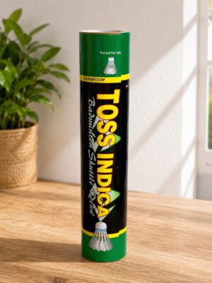 Tall green and black cylindrical packaging for Toss India badminton shuttlecocks on a wooden table, indoors.
