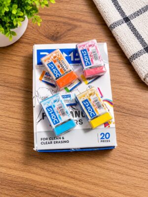 Assorted colorful erasers scattered on a white box labeled 'for clean & clear erasing' on a wooden desk with a potted plant nearby.