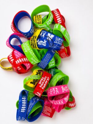 Colorful silicone wristbands with printed messages like Best Friends Forever, arranged in a pile on white background