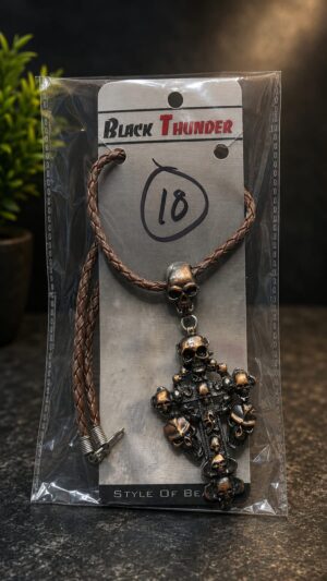 Brown braided leather necklace with a large skull pendant and multiple smaller skull charms on a metal cross, displayed on a pad labeled Black Thunder